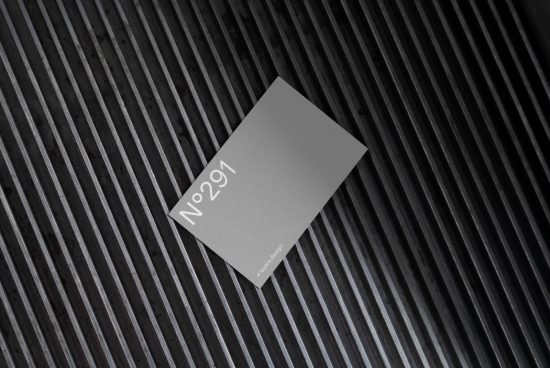 Elegant business card mockup lying on textured striped surface, minimalist design, graphic designers asset, creative presentation, black and white.