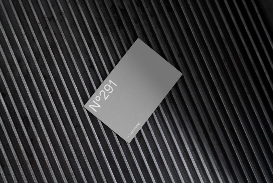 Gray business card mockup tilted on ridged dark background