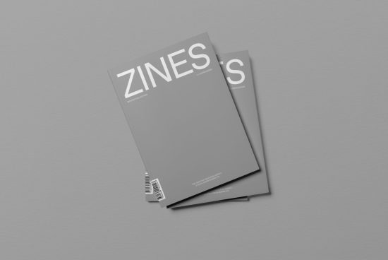 Magazine mockup with two grey cover zines on a plain background, ideal for presenting editorial designs and layouts.