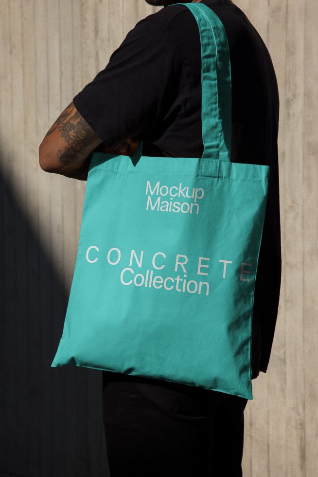 Person carrying teal tote bag mockup with white branding text on it, ideal for presenting merchandise designs and logos.