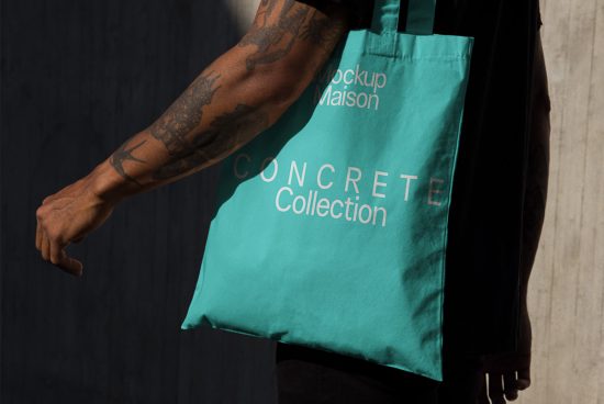 Tattooed arm holding a teal tote bag mockup with the text Concrete Collection, ideal for showcasing design work.