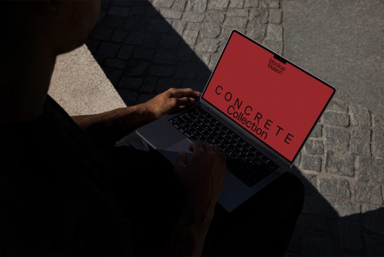 Person using laptop with red screen mockup, tattooed arms, outdoor setting, ideal for showcasing designs, web templates, and graphics.