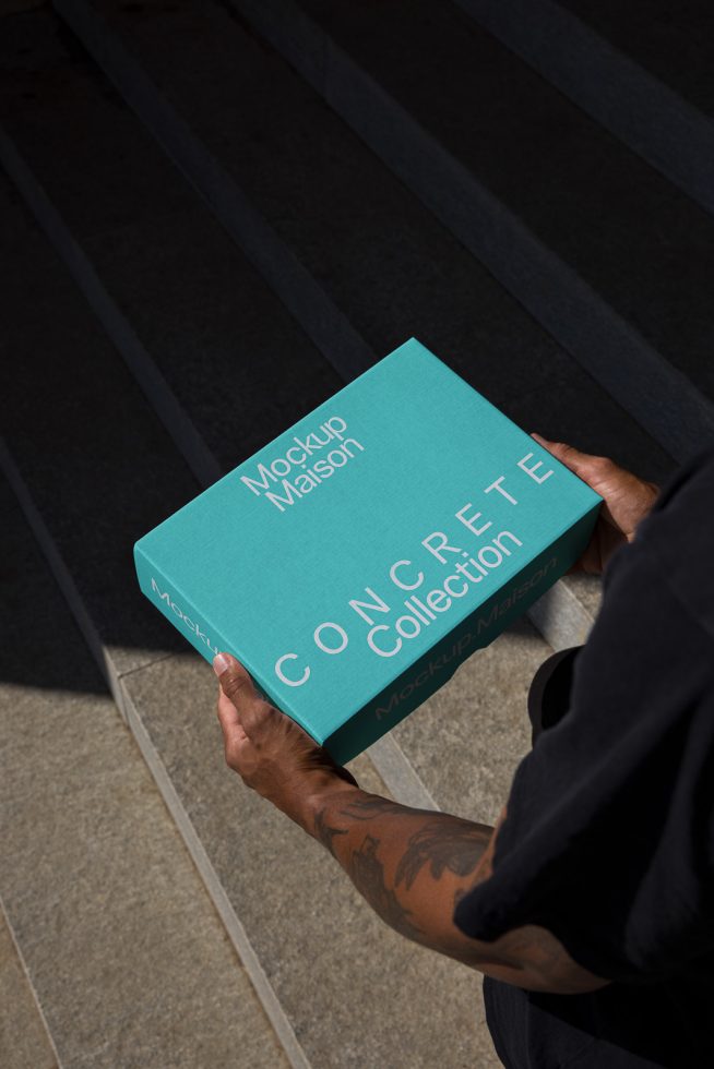 Person holding a Mockup Mason book with CONCRETE Collection text. Ideal for designers seeking mockup graphics in urban settings.