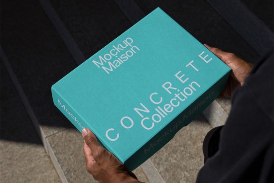 Person holding a teal book mockup with 'Mockup Maison CONCRETE Collection' text for graphic design and packaging presentation.