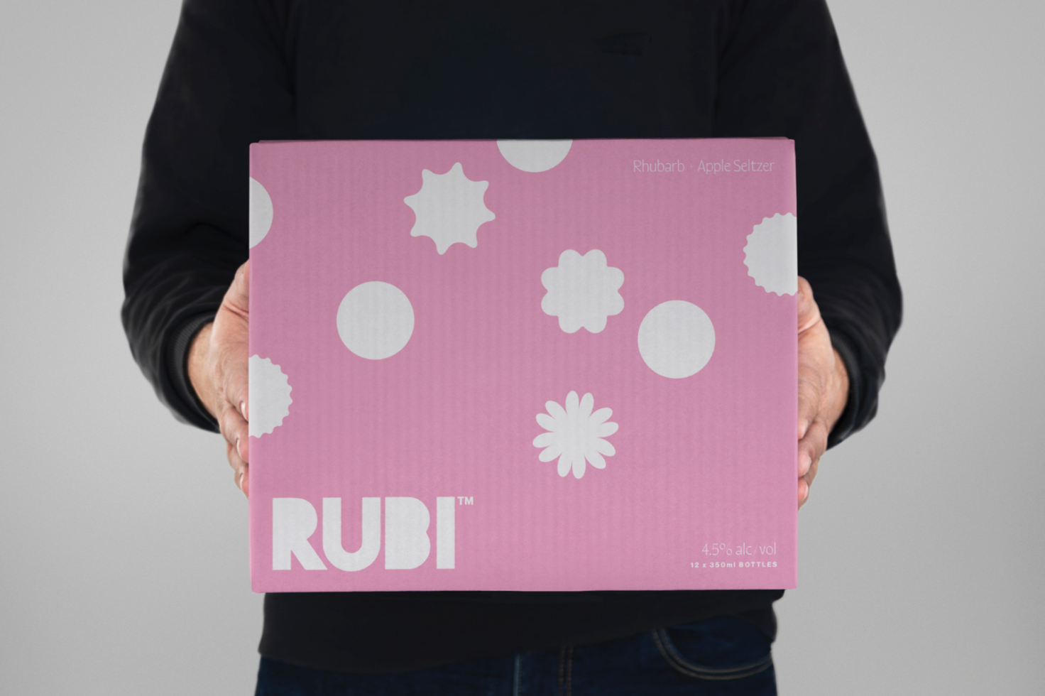 Person holding a pink product box with white patterns and text for branding mockup, packaging design displayed by designer for portfolio.