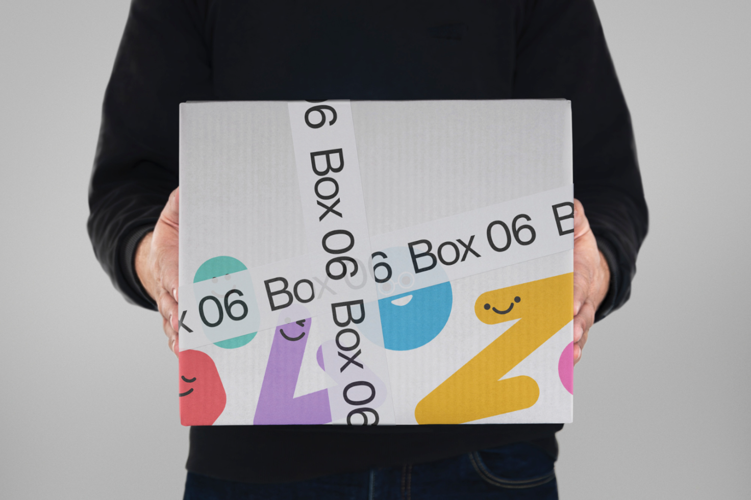 Person holding a box with colorful, playful graphics, ideal for packaging design mockup, design assets, creative templates.