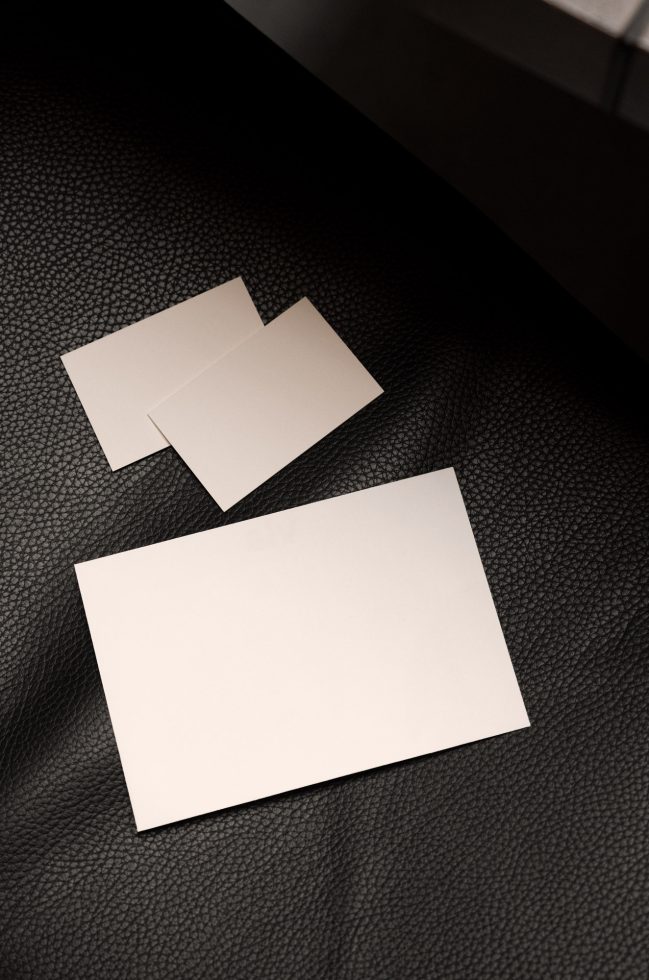 Elegant business card mockup on dark textured leather surface, angled view, suitable for design presentation and branding.