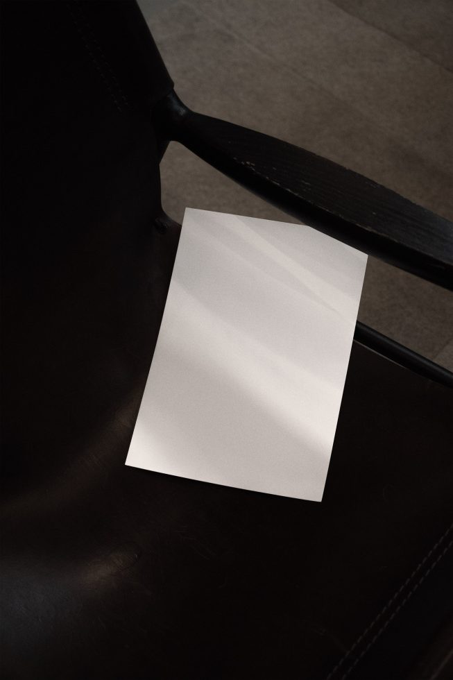 Blank A4 paper mockup on a dark leather chair, ideal for presenting brochure designs and stationery branding for designers.