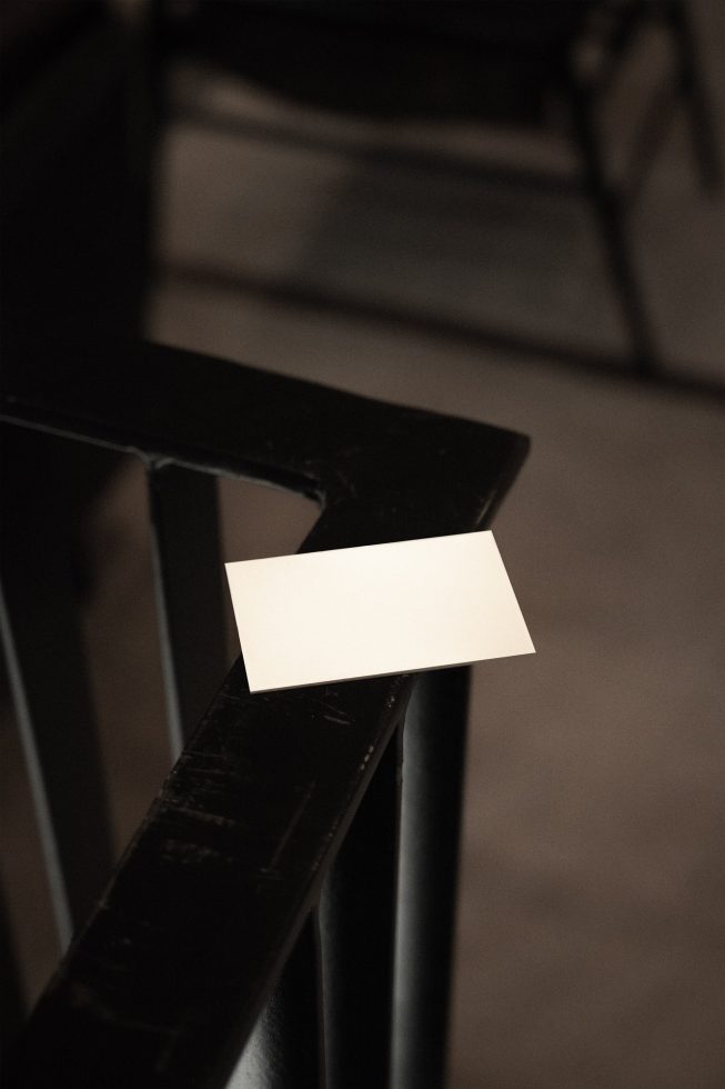 Blank business card mockup on dark chair, minimalist design, versatile presentation tool for branding, stationery, and identity graphics.