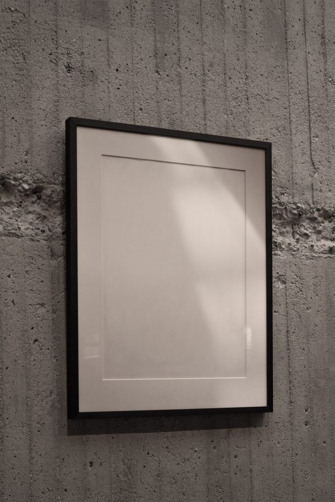 Blank framed poster on concrete wall, ideal for mockups, interior design, minimalist presentations, and art showcases.