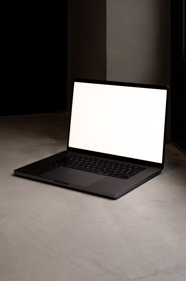 Laptop mockup on a dark surface, blank screen for design presentation, modern and sleek device, digital asset for graphic designers.