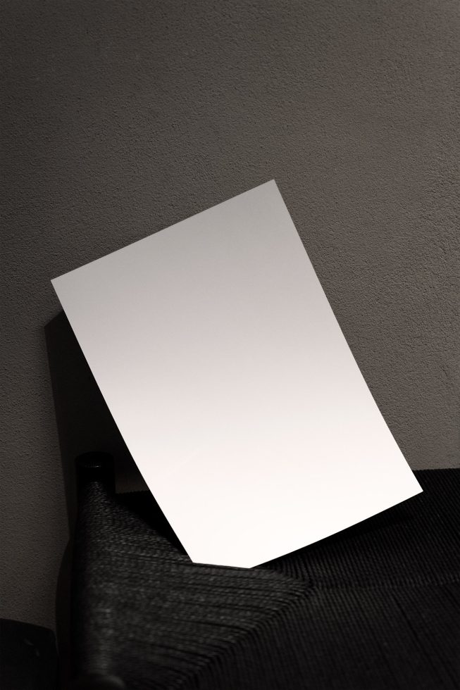 Blank white poster mockup on a textured surface with a shadow gradient, ideal for showcasing design, graphics, and typography work.