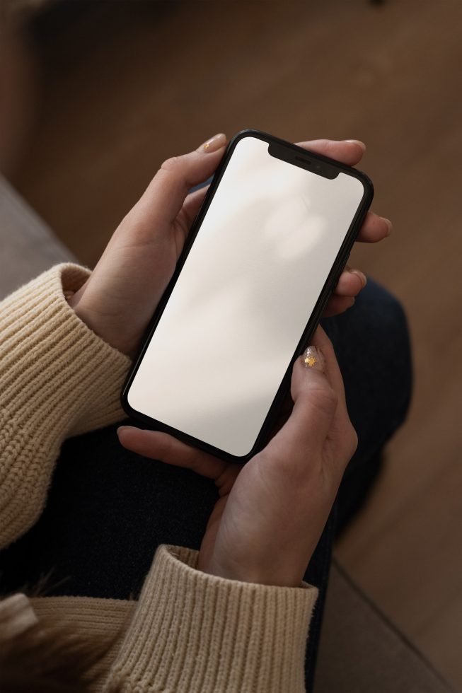 Person holding smartphone with blank screen in cozy setting, ideal for mockup, display design, app presentation, digital asset.