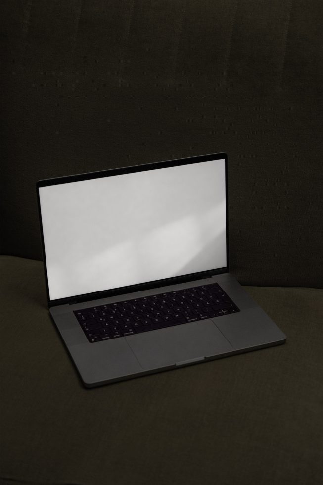 Laptop on dark fabric background, blank screen for mockup designs, ideal for presenting digital templates and user interface layouts.