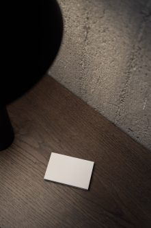 Blank business card mockup on dark wood floor with concrete wall texture overhead