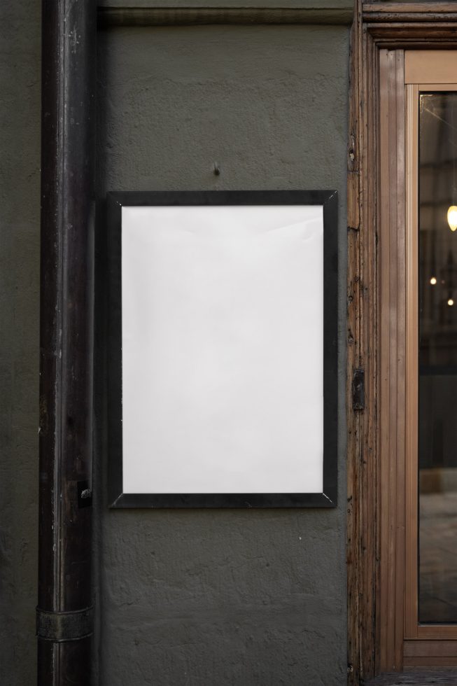 Blank outdoor billboard mockup on a wall by a wooden window frame, ideal for poster design display in urban settings for designers.