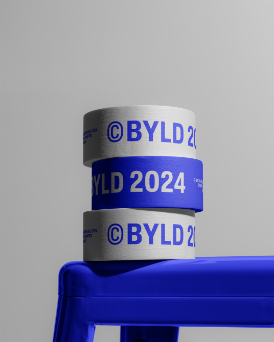 Stack of blue and white branded adhesive tape rolls on vibrant blue stool with unique presentation style, ideal for mockup graphics design.