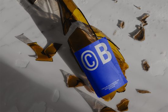 Broken beer bottle with blue label mockup on marble surface, product packaging, shattered glass, design showcase.
