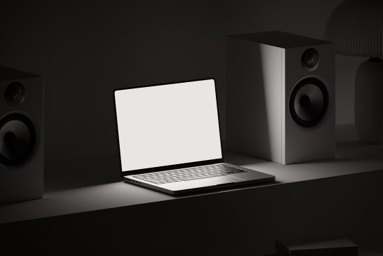 Laptop mockup on desk with blank screen surrounded by speakers, ideal for presenting UI designs, templates, and digital graphics.