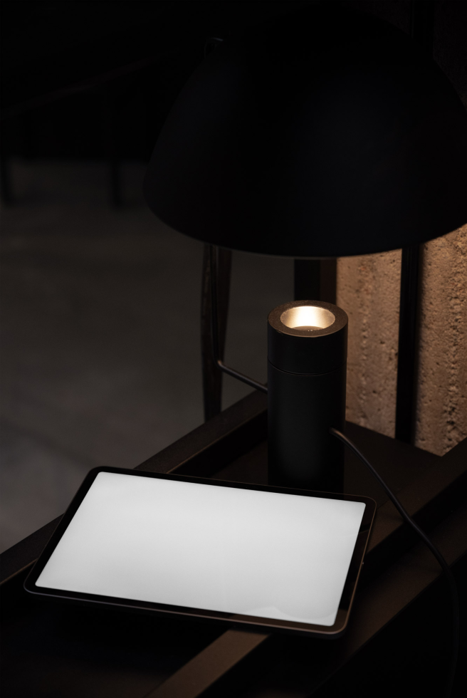 Minimalist tablet mockup on a dark wooden desk with a stylish lamp, ideal for showcasing UI/UX designs, digital art, and graphics.