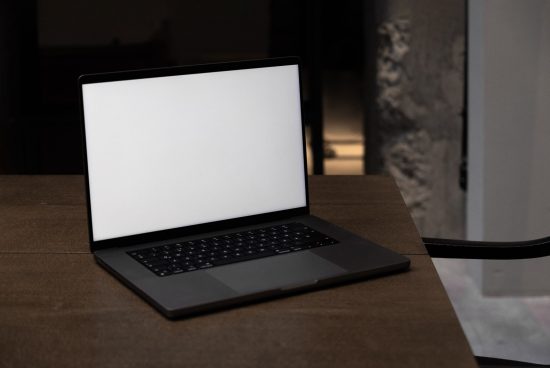 Laptop on desk mockup in a dimly lit room with blank screen for template design, featuring modern sleek design, suitable for graphics display.