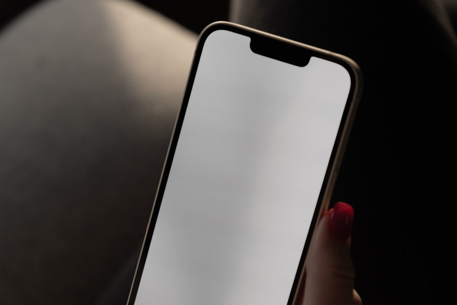 Smartphone mockup held in hand with blank screen for design presentation, isolated on a dark background, editable digital asset.