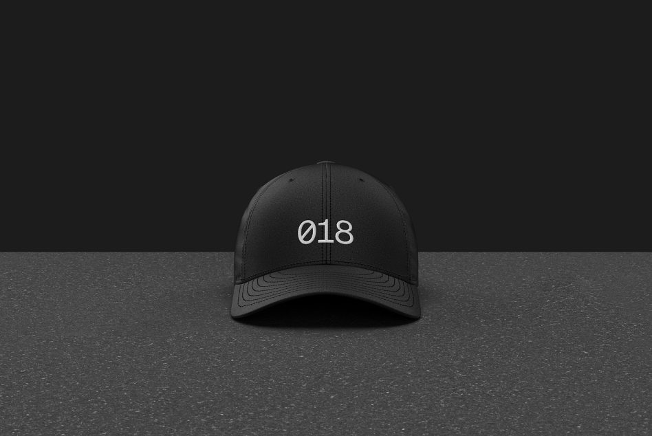 Black baseball cap mockup with number 018 on textured background, ideal for logo presentation and branding design.