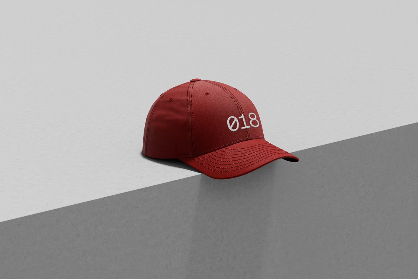 Red baseball cap mockup with stylish embroidery on white textured background, perfect for hat design presentations and fashion graphics.