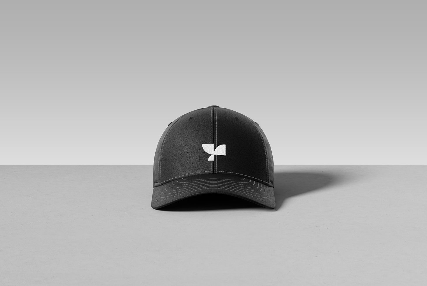 Black baseball cap with white logo front view on a gray background, perfect for mockup designs, merchandise presentation, and branding projects.