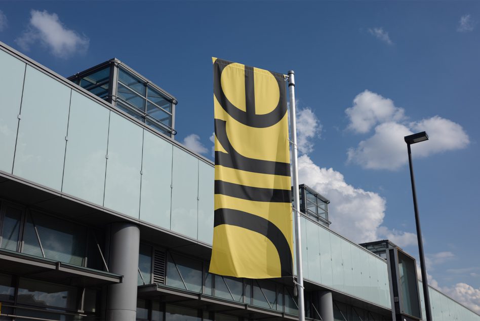 Outdoor flag mockup on a pole displaying modern design elements, positioned in front of a building with glass elements, ideal for graphic designers and marketers.