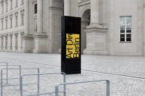 Yellow vertical signage on classical stone courtyard with neoclassical columns