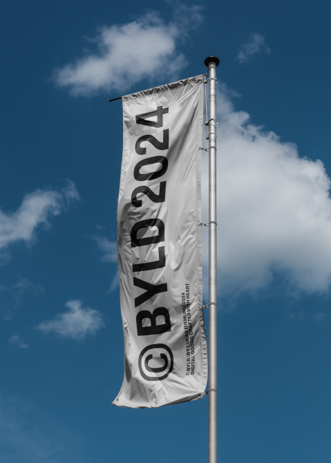 Flag mockup against blue sky with clouds displaying BYLD2024 logo. Ideal for designers seeking realistic flag mockup templates for presentations and design showcase.