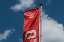 Red flag on pole with BYLD logo, white stripe, cloud sky backdrop