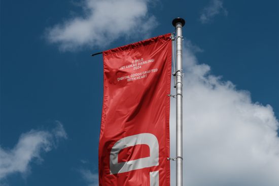 Red flag attached to metal pole against blue sky with white clouds. Perfect for product branding mockups, print templates, and advertising graphics.
