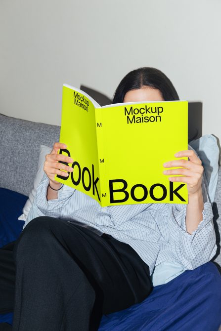 Woman seated with vibrant yellow mockup magazine covering face, ideal for design showcase, realistic print mockup for presentations.