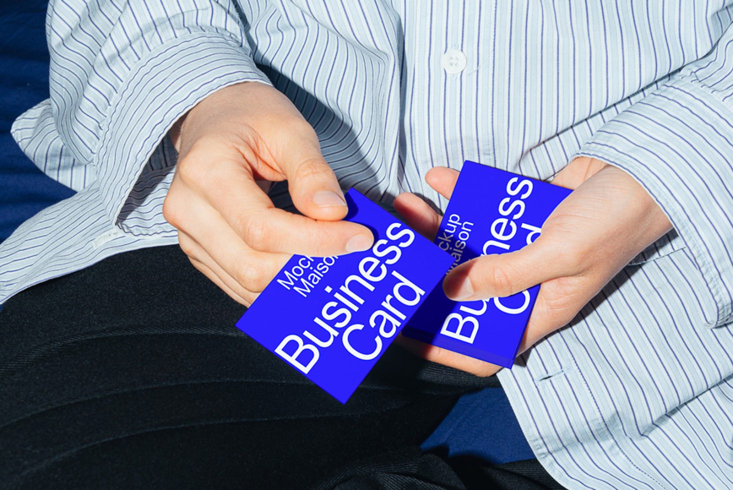 Person holding blue business card mockup for design presentation, showcasing professional branding on textured cardstock, ideal for graphic designers.