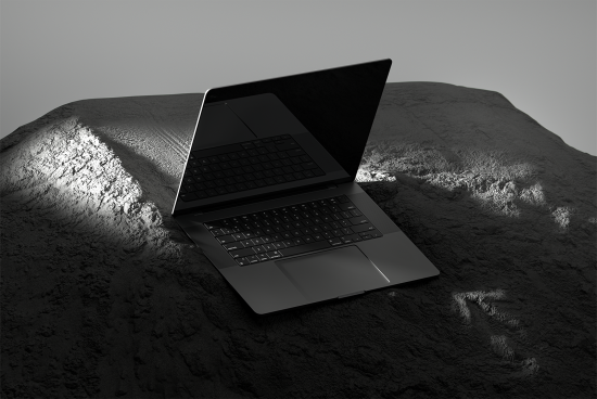 Laptop mockup on rough stone surface with dramatic lighting ideal for showcasing UX UI design digital assets for designers mockups templates graphics fonts