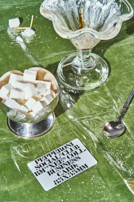 Overhead shot of vintage glassware with sugar cubes on textured green fabric with business card