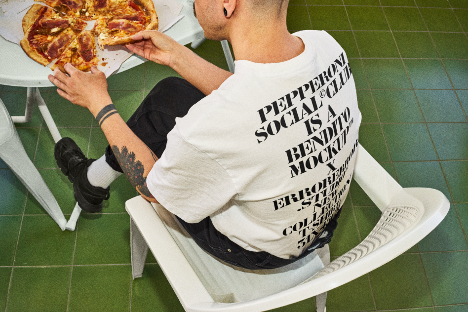 Man in graphic t-shirt eating pepperoni pizza. Ideal for product mockups, t-shirt design templates, and graphic design assets. Green tiled floor.