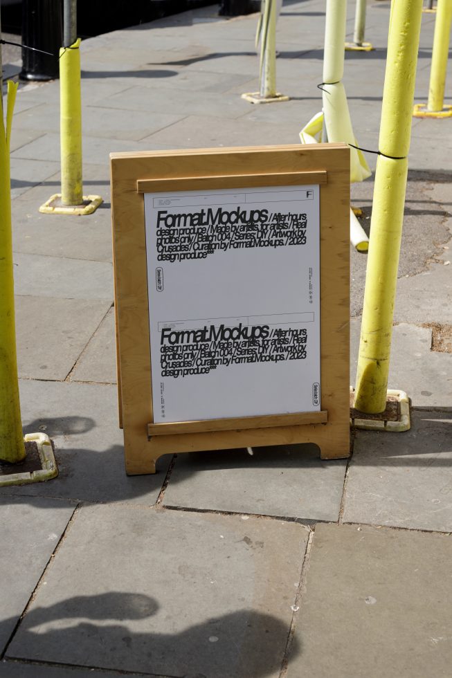 Outdoor format mockup on a wooden stand showing black text on white paper, surrounded by yellow poles. Keywords: mockup, template, poster design, street.