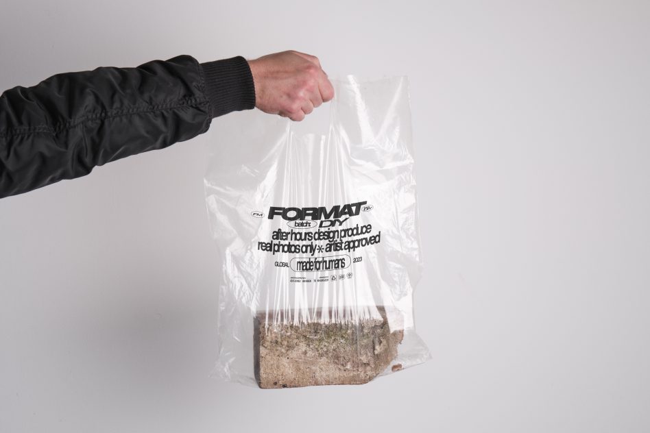 Hand holding a clear plastic bag with text, containing a chunk of mossy stone. Ideal for designers needing mockups or branding presentation materials.