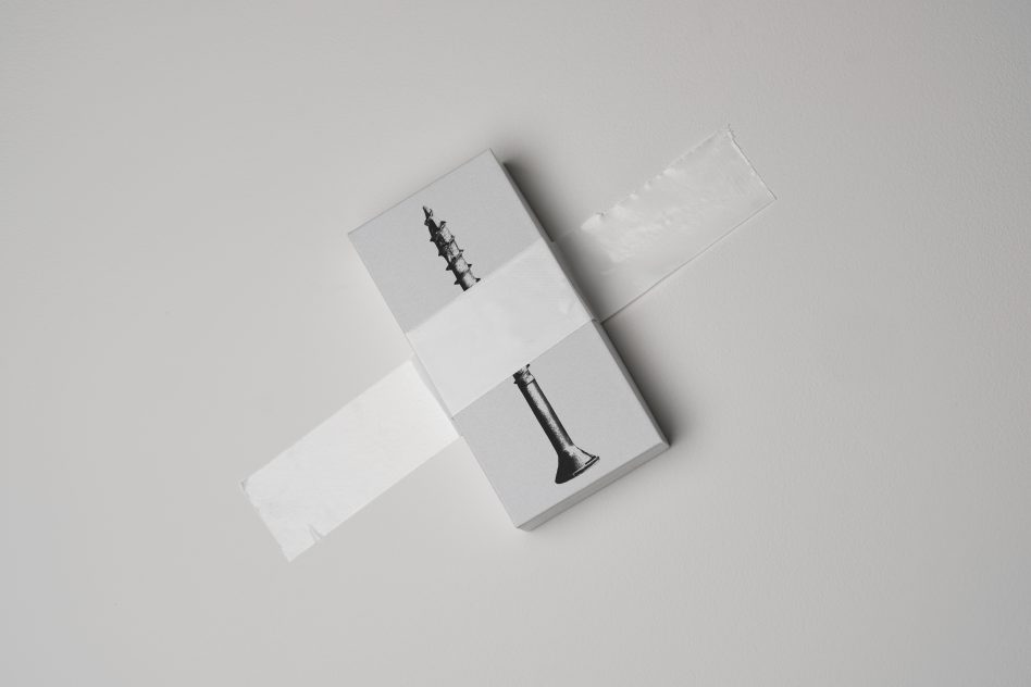 Minimalist grey box with a black and white screw image taped to a white surface ideal for mockups packaging design presentations designers SEO keywords