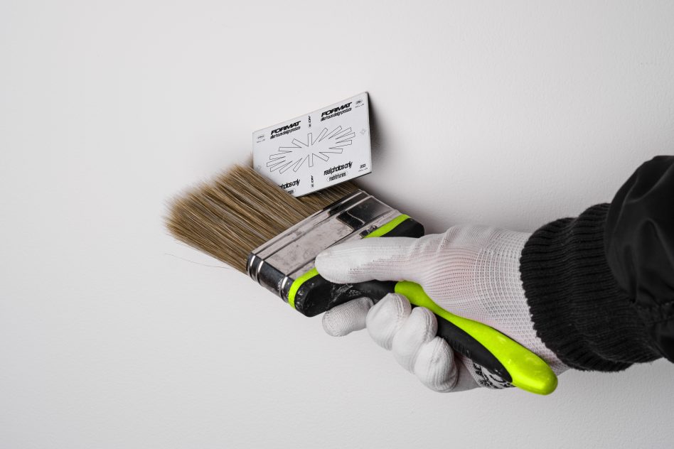 Hand in glove holding paintbrush for precise wall painting with stencil, ideal for interior design. Mockup showing painting tool in use. Keywords: Mockup, Painting, Design.