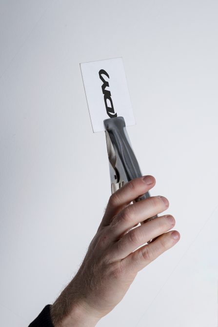 Hand holding pen with white label mockup against light background
