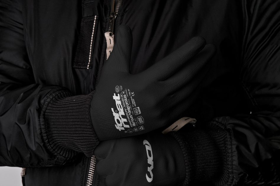 Close-up of person wearing black insulated gloves and a black zip-up jacket suitable for cold weather. Ideal for winter wear, warmth, and comfort.