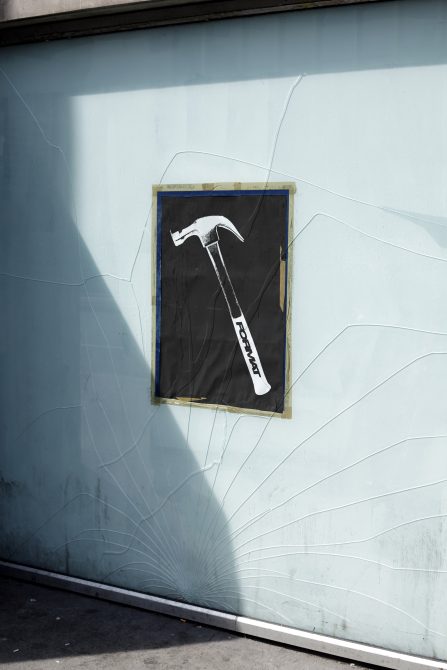 Grunge-style hammer poster mockup on a cracked wall with shadow overlay. Perfect for showcasing urban-themed graphic designs, street art, and poster templates.