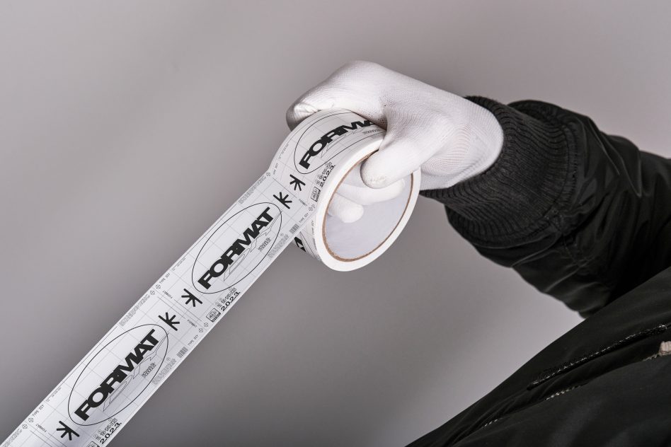 Person in white gloves holding a roll of custom printed tape with text Format. Great for branding mockups, packaging design templates, and graphic resources.