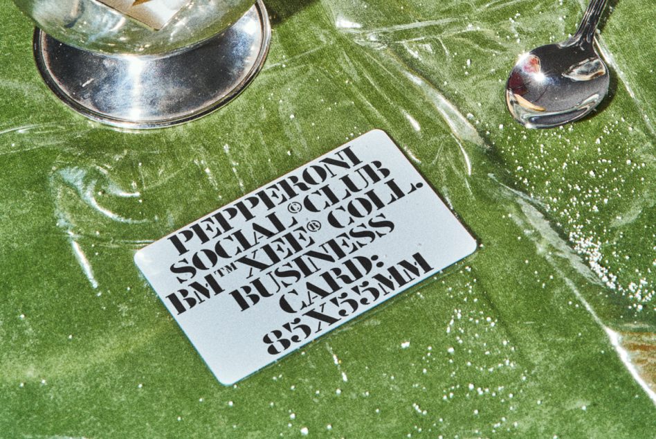 Top view silver spoon on textured green fabric with mockup business card displayed