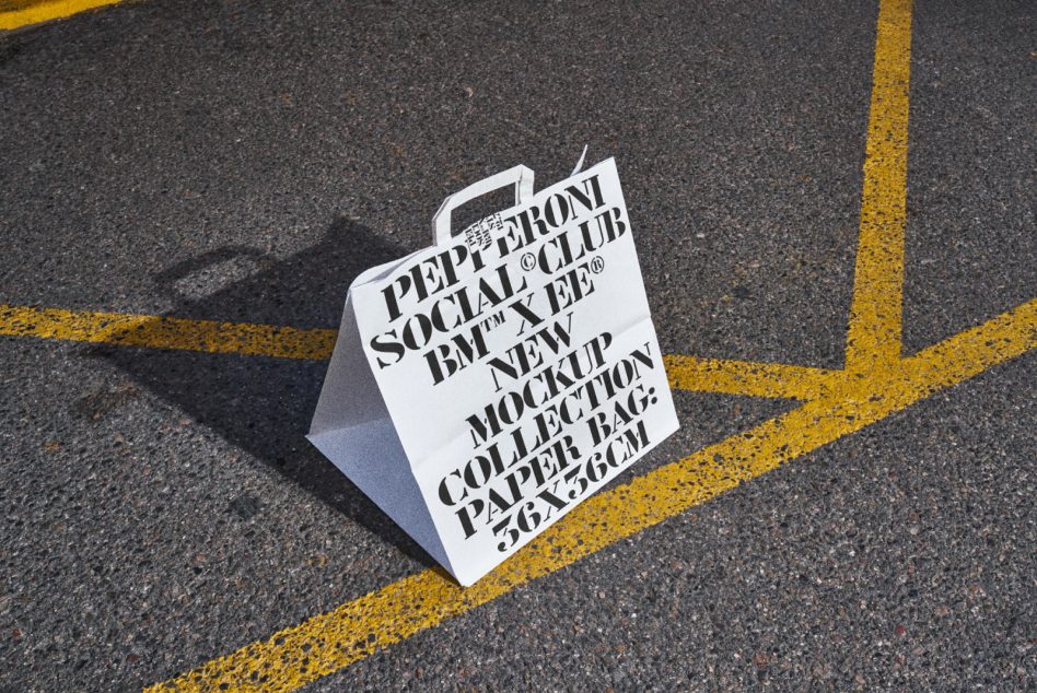 Paper bag mockup on asphalt ground with bold graphic font design, ideal for showcasing packaging design, product branding, and graphic templates for designers.