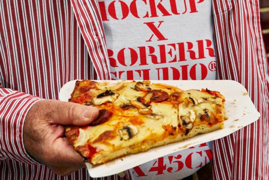Person in striped shirt holding a slice of pizza, torso visible with red text on shirt. Suitable for mockup templates or branding design, food theme graphics.